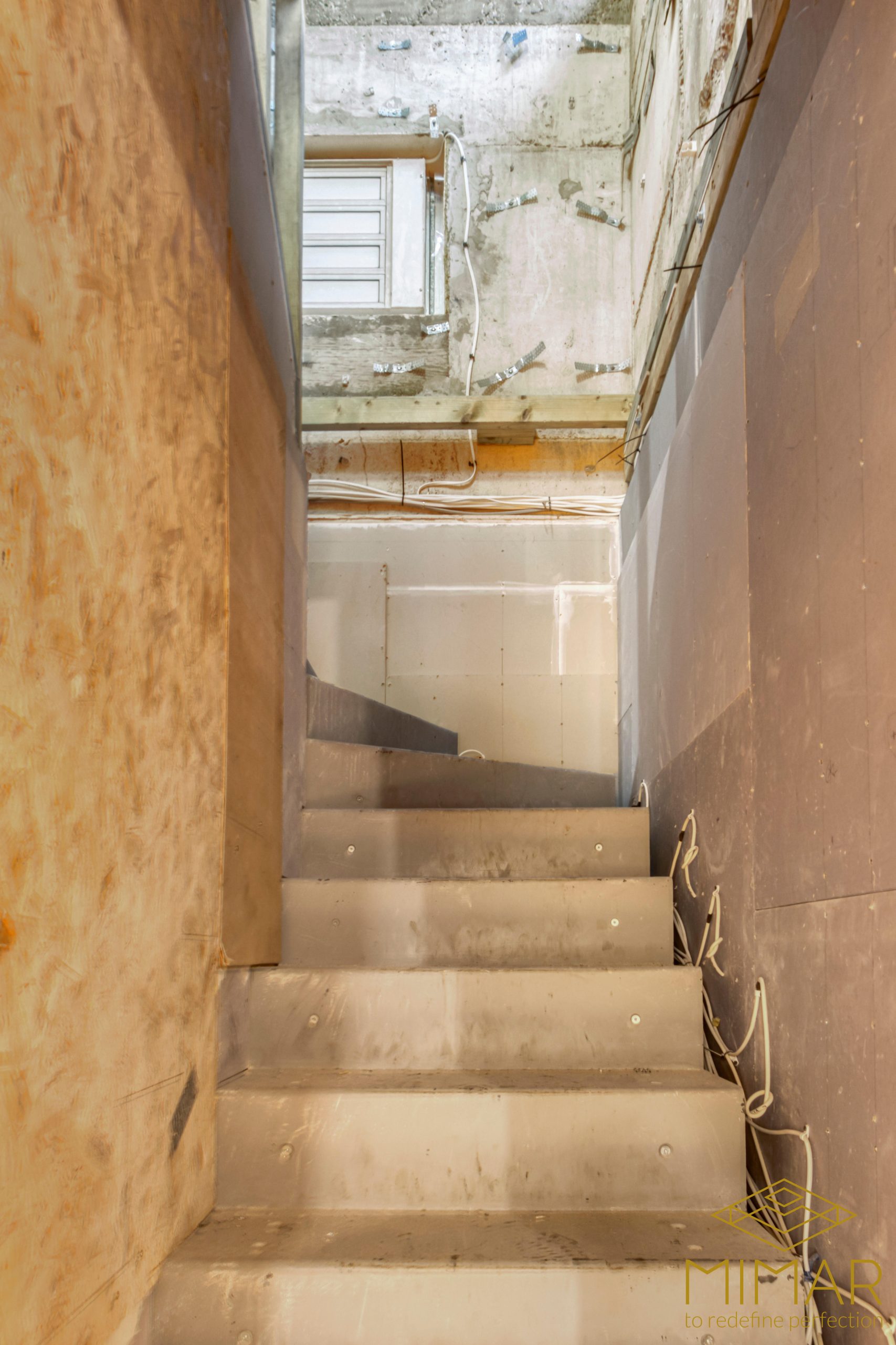 A partially constructed basement stairway with visible wiring and unfinished walls.