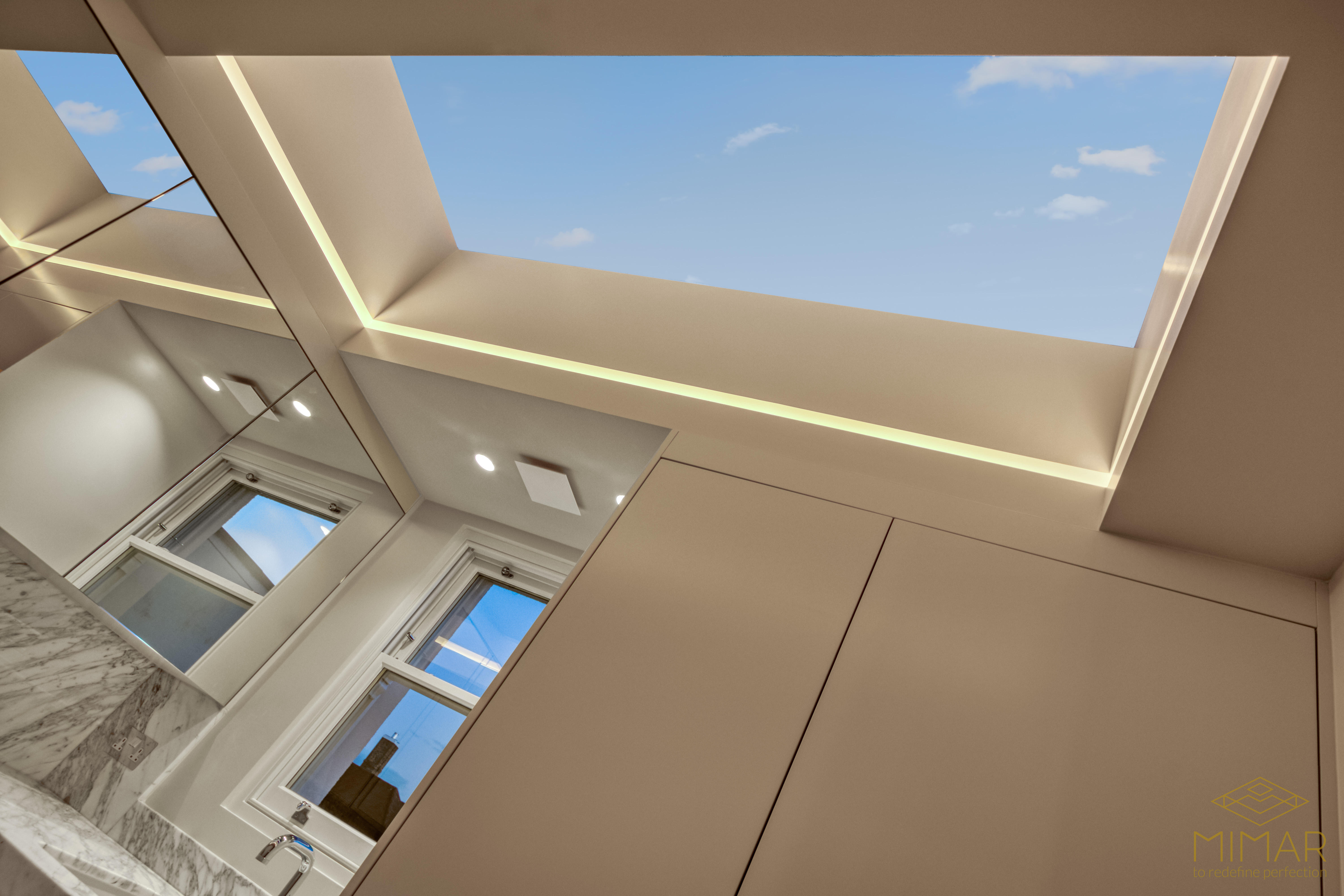 Interior view of a modern bathroom with a large skylight providing natural light, marble countertop, and sleek cabinetry.