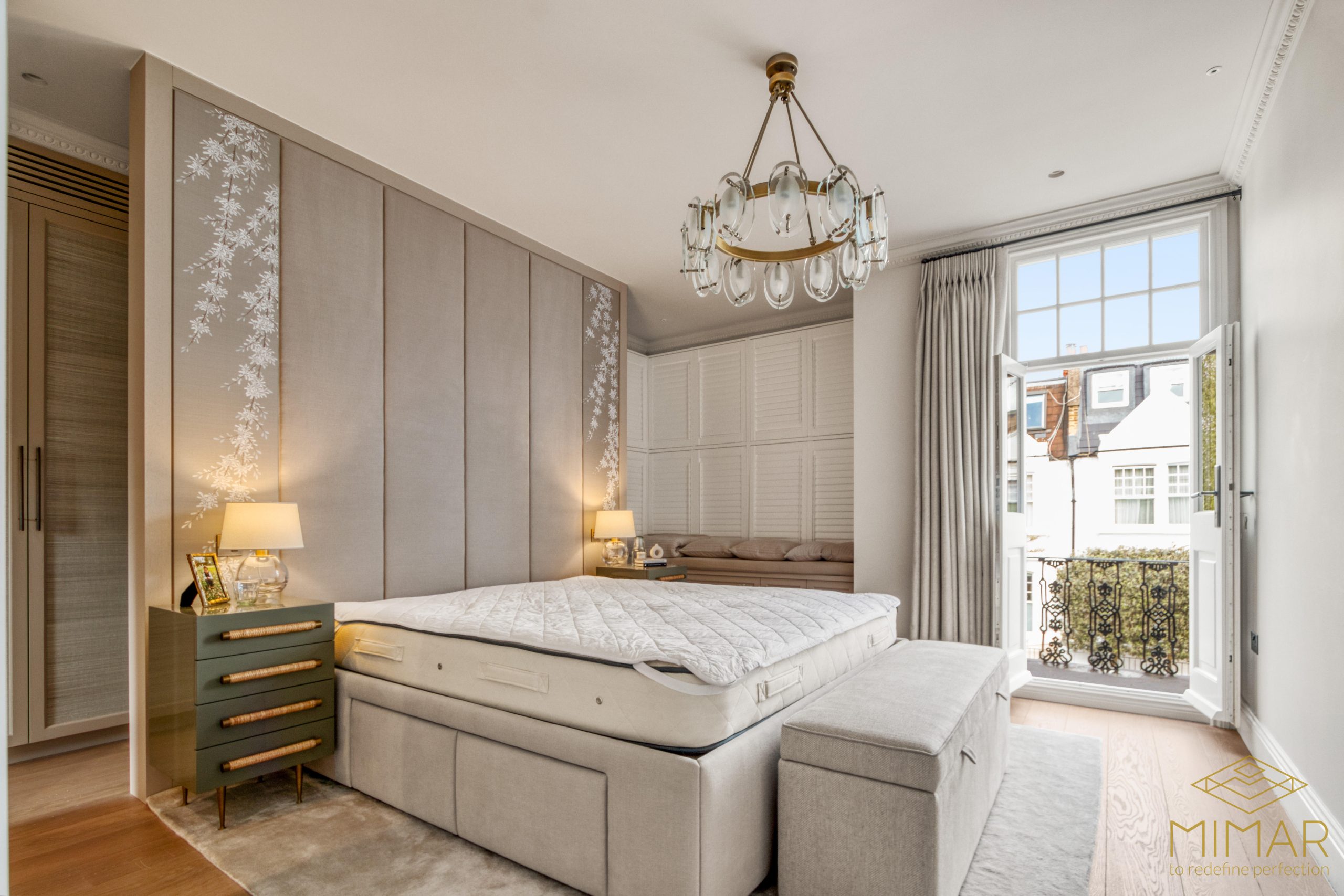 Luxuriously refurbished bedroom with elegant decor, featuring a large bed, modern chandelier, and open French doors leading to a balcony.