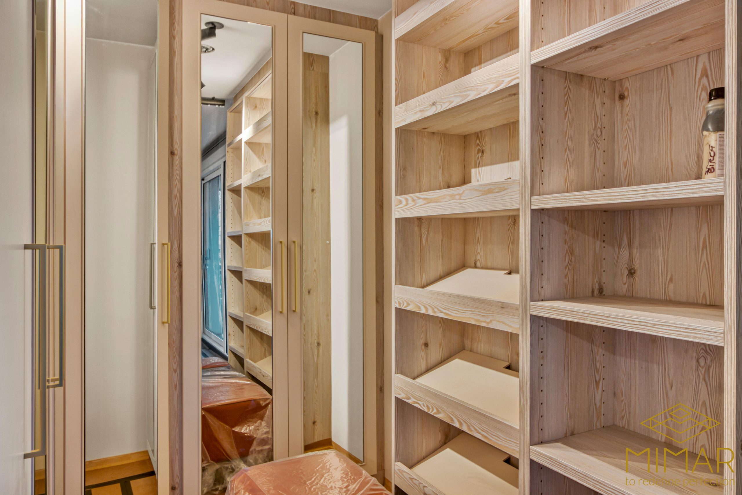 A custom-built wardrobe with mirrored doors and wooden shelving in a modern interior.