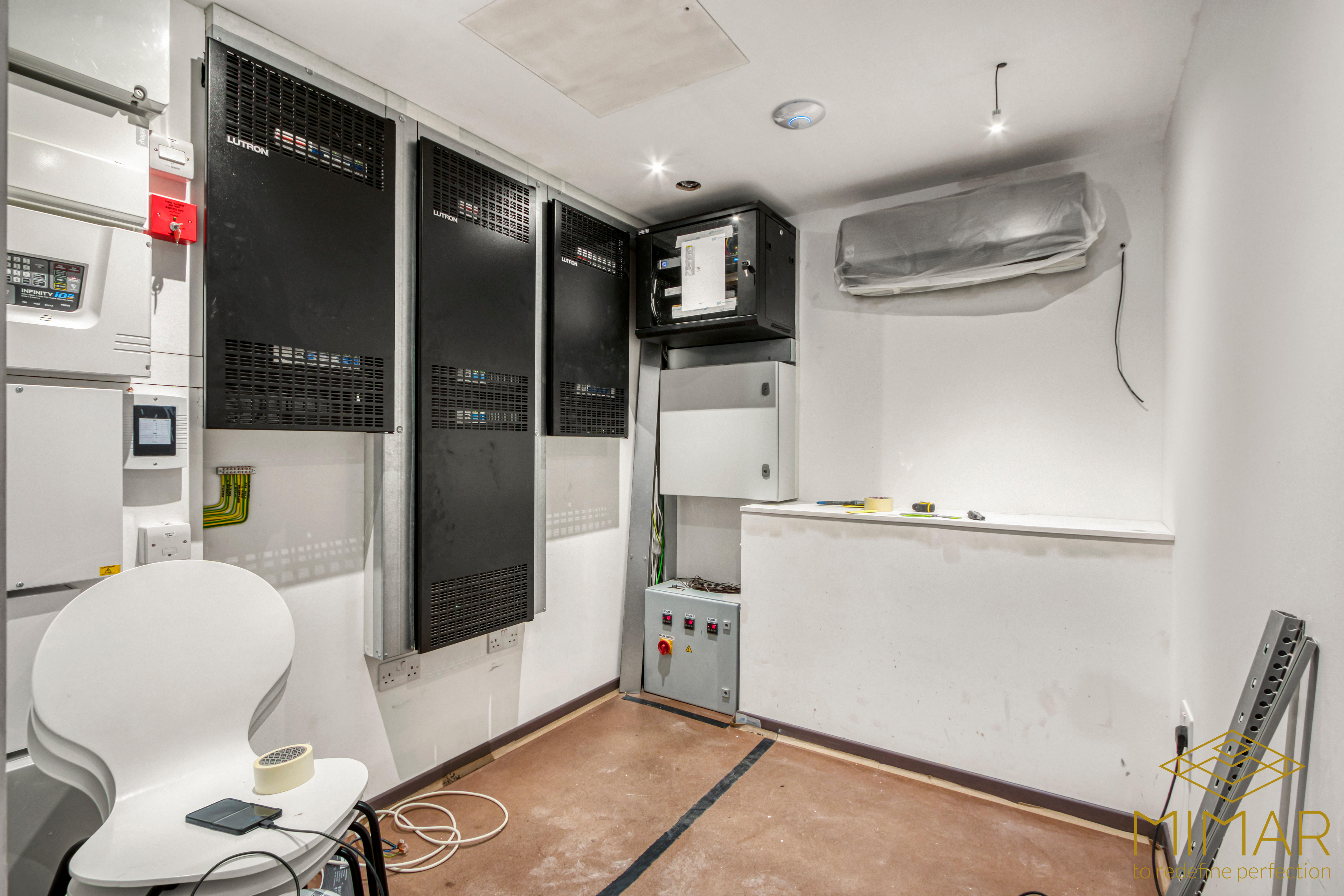 Room with electrical panels and wiring installations, featuring control boxes and ventilation system.