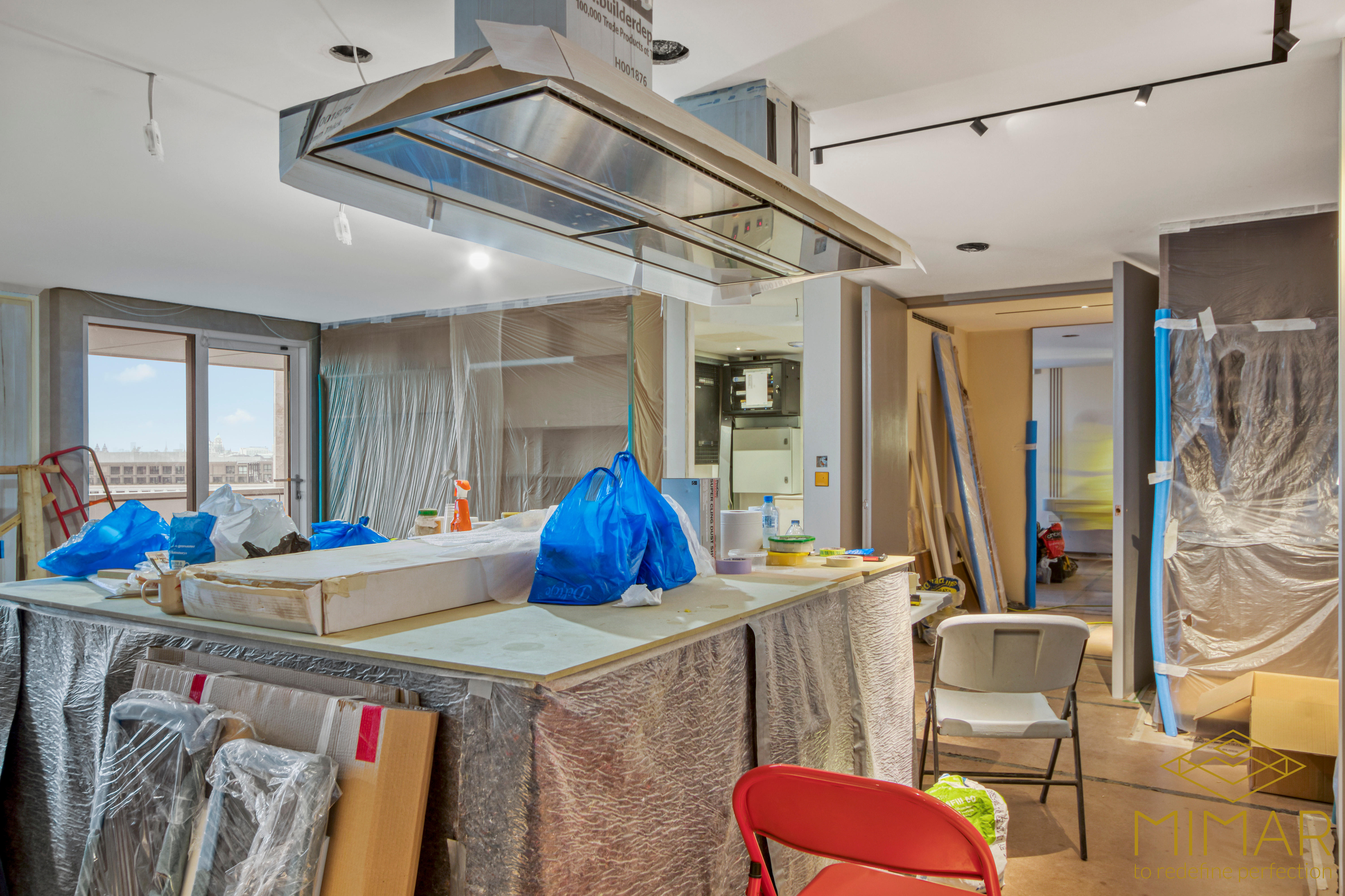 Image showing a kitchen area under renovation with covered surfaces, tools, and materials scattered around.