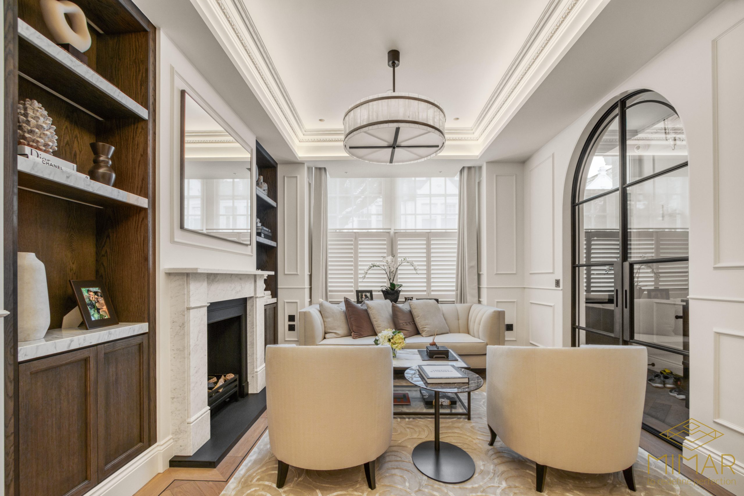 A beautifully remodeled living room with elegant furniture, a fireplace, and custom shelving, showcasing a sophisticated interior design.