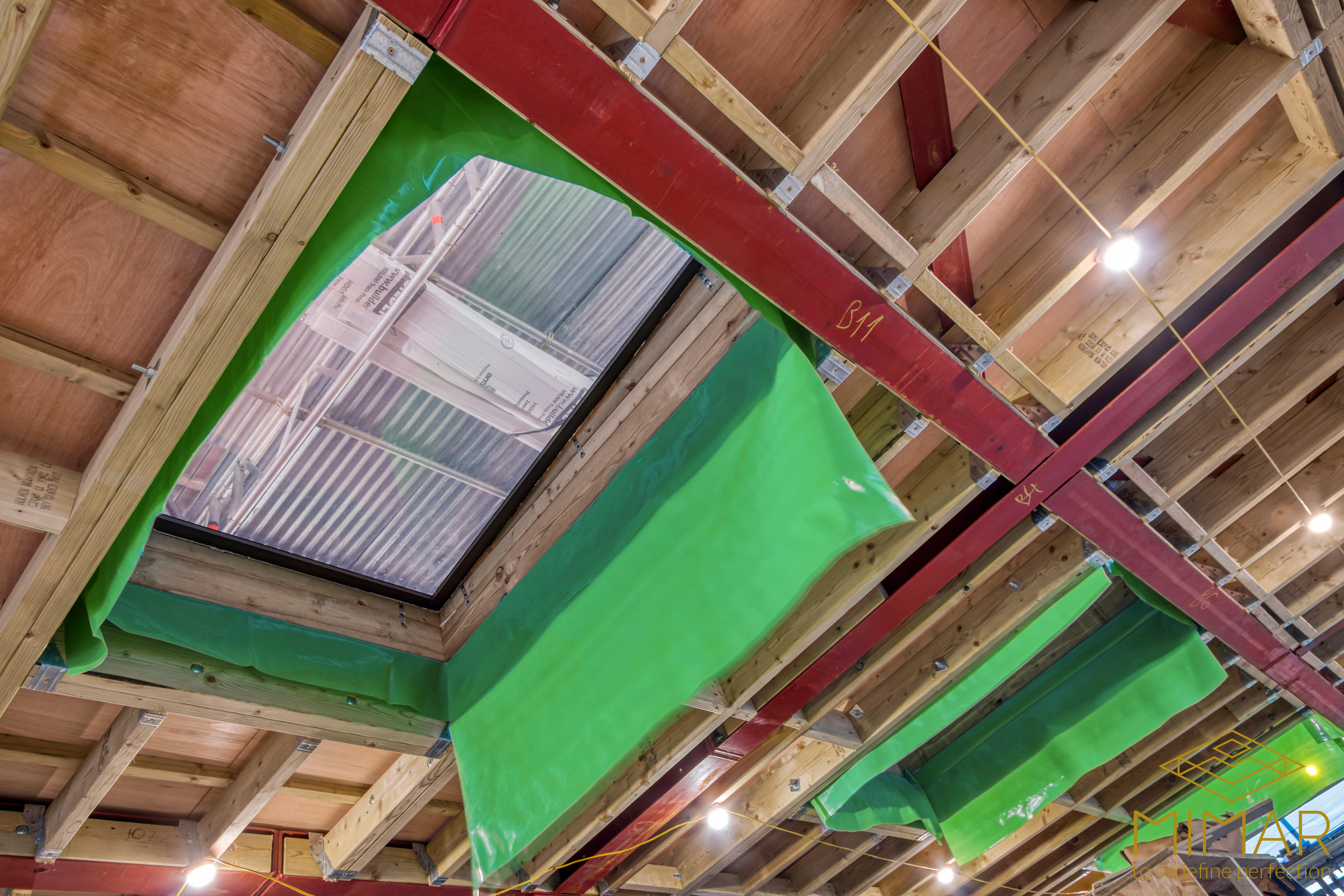 Image showing the interior view of a loft under conversion, featuring wooden beams and steel support structures with green protective sheeting.