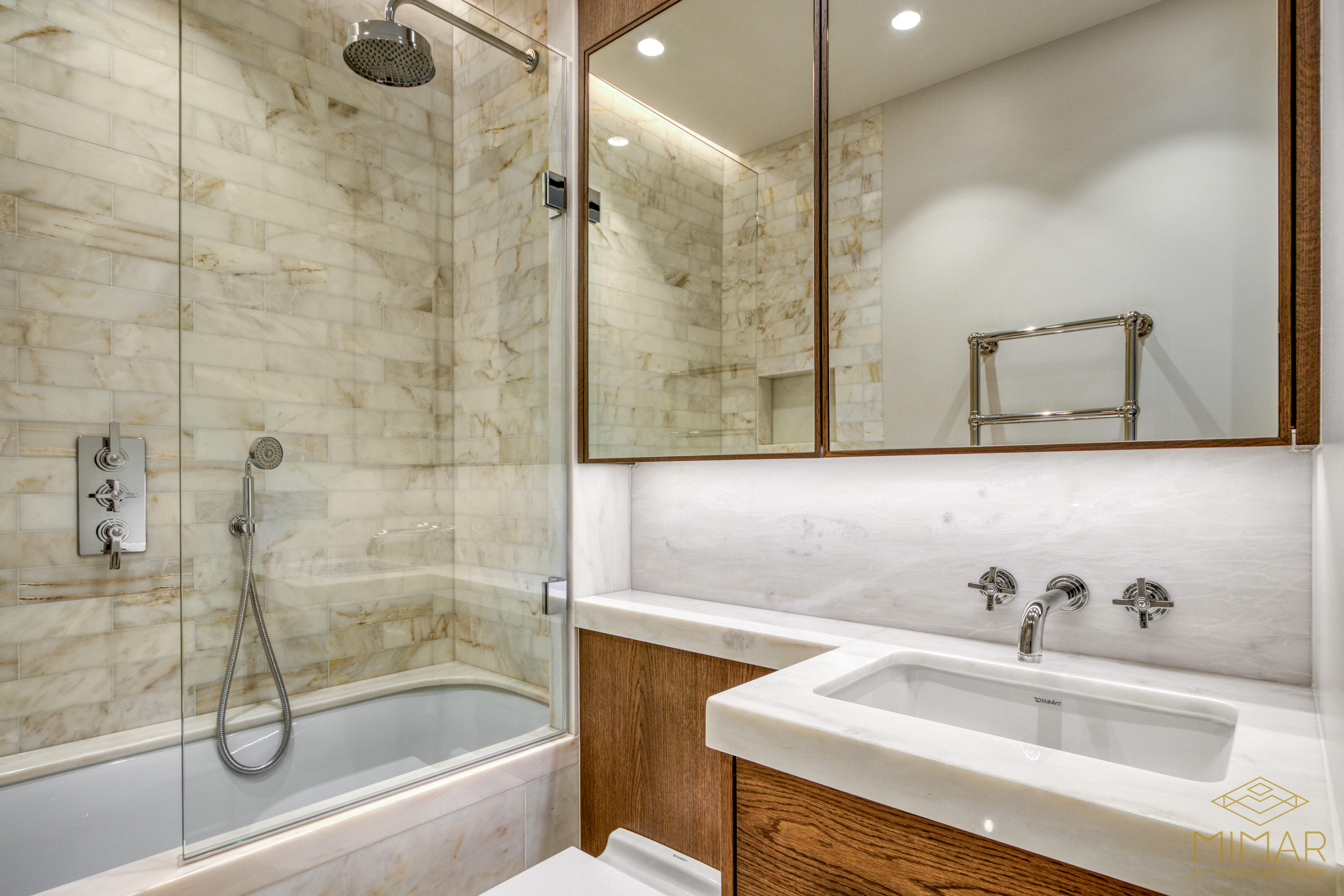 Modern bathroom with glass-enclosed shower, marble tiles, and wooden vanity.