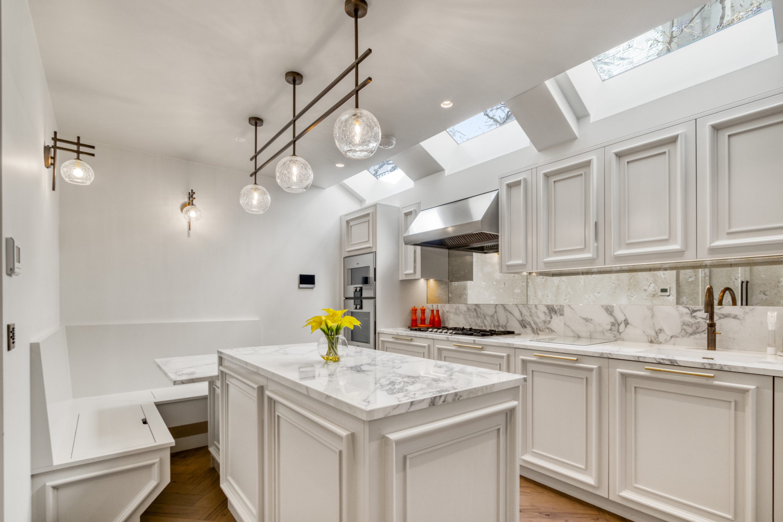 Modern kitchen with marble countertops, white cabinetry, and pendant lighting.