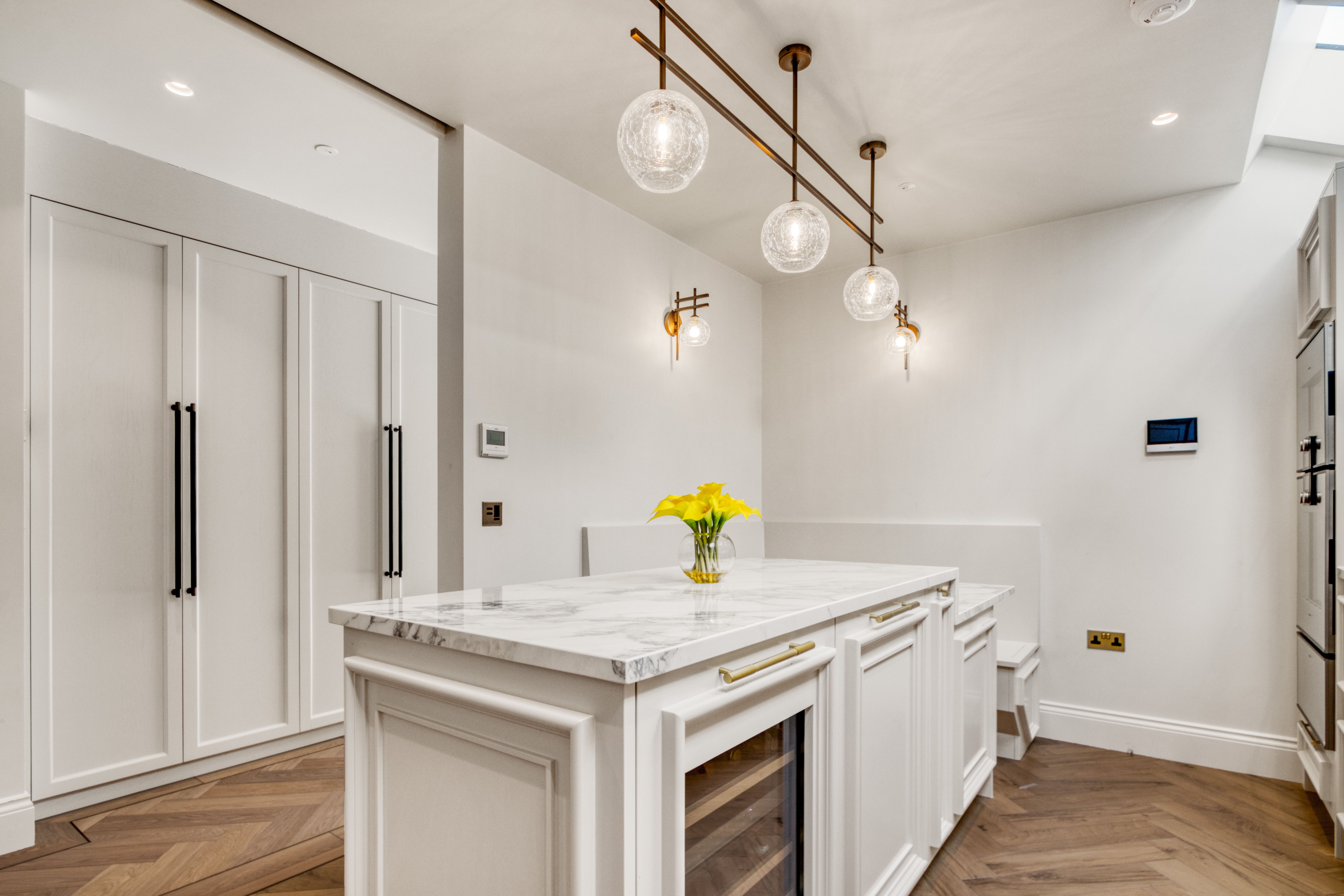 A modern kitchen with a marble island, sleek cabinetry, pendant lighting, and integrated appliances.