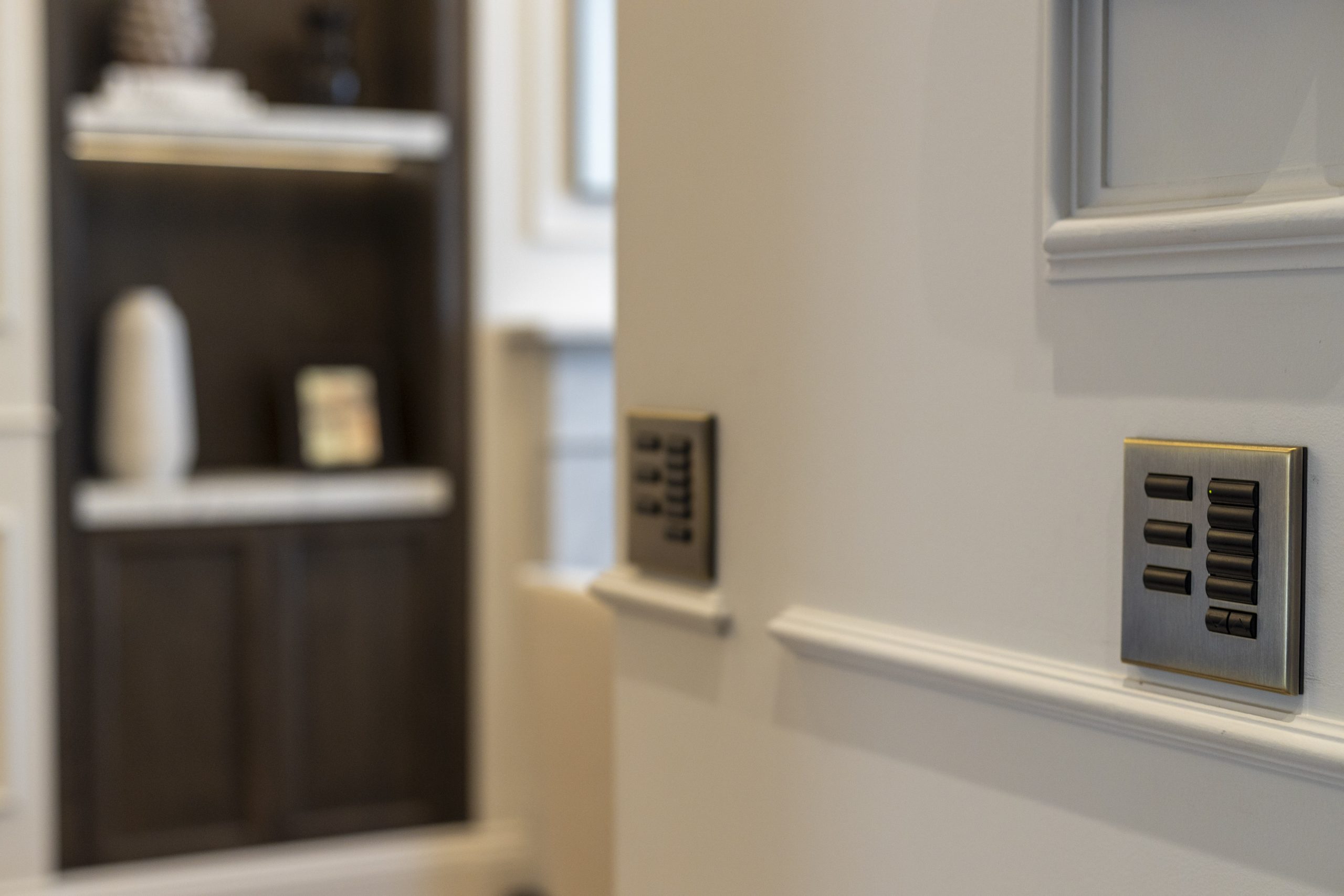 A close-up view of modern light switch panels installed on a wall, featuring a sleek metallic design with multiple buttons.