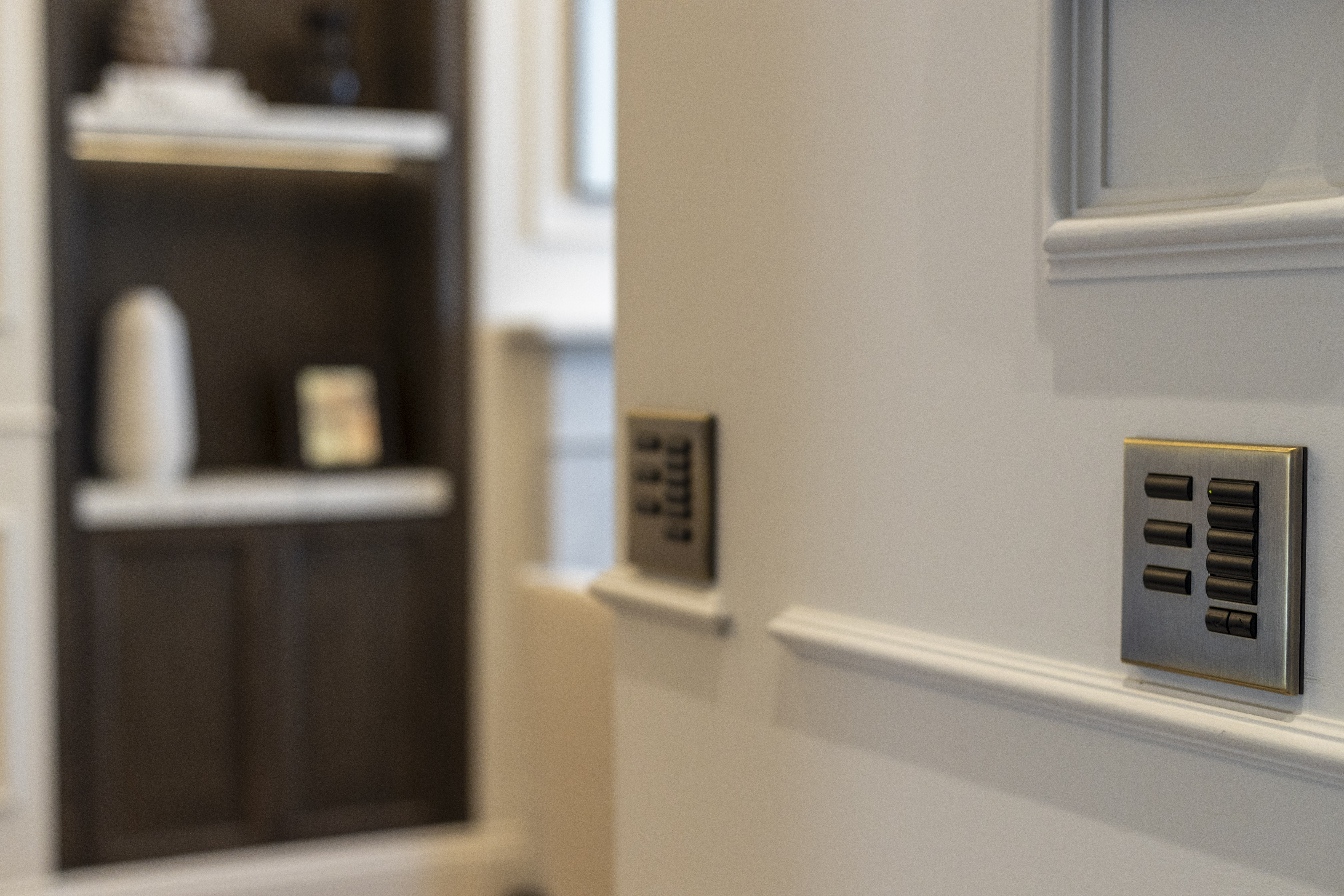 A close-up view of modern light switch panels installed on a wall, featuring a sleek metallic design with multiple buttons.