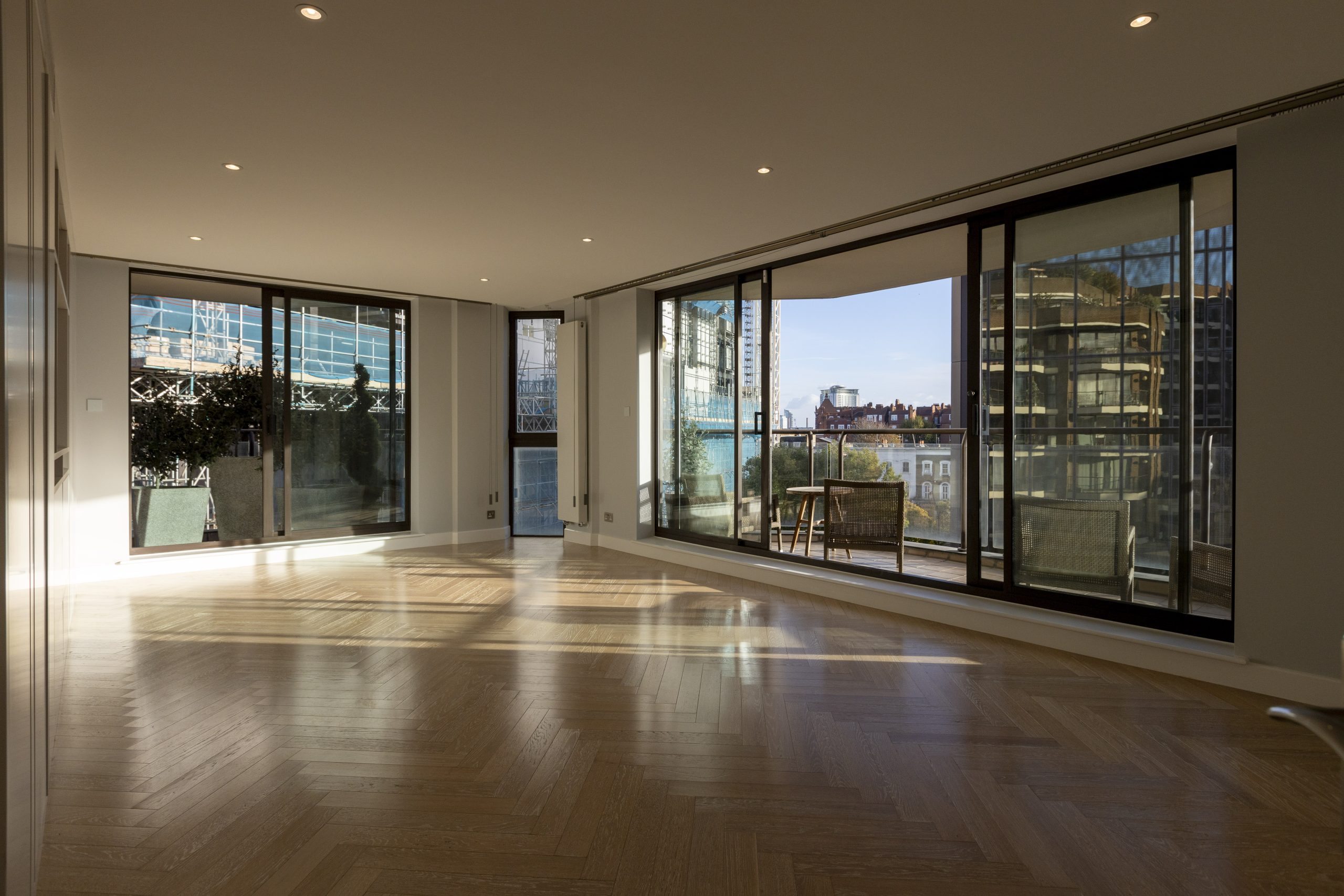 Modern empty living room with large sliding glass doors leading to a balcony with city view.