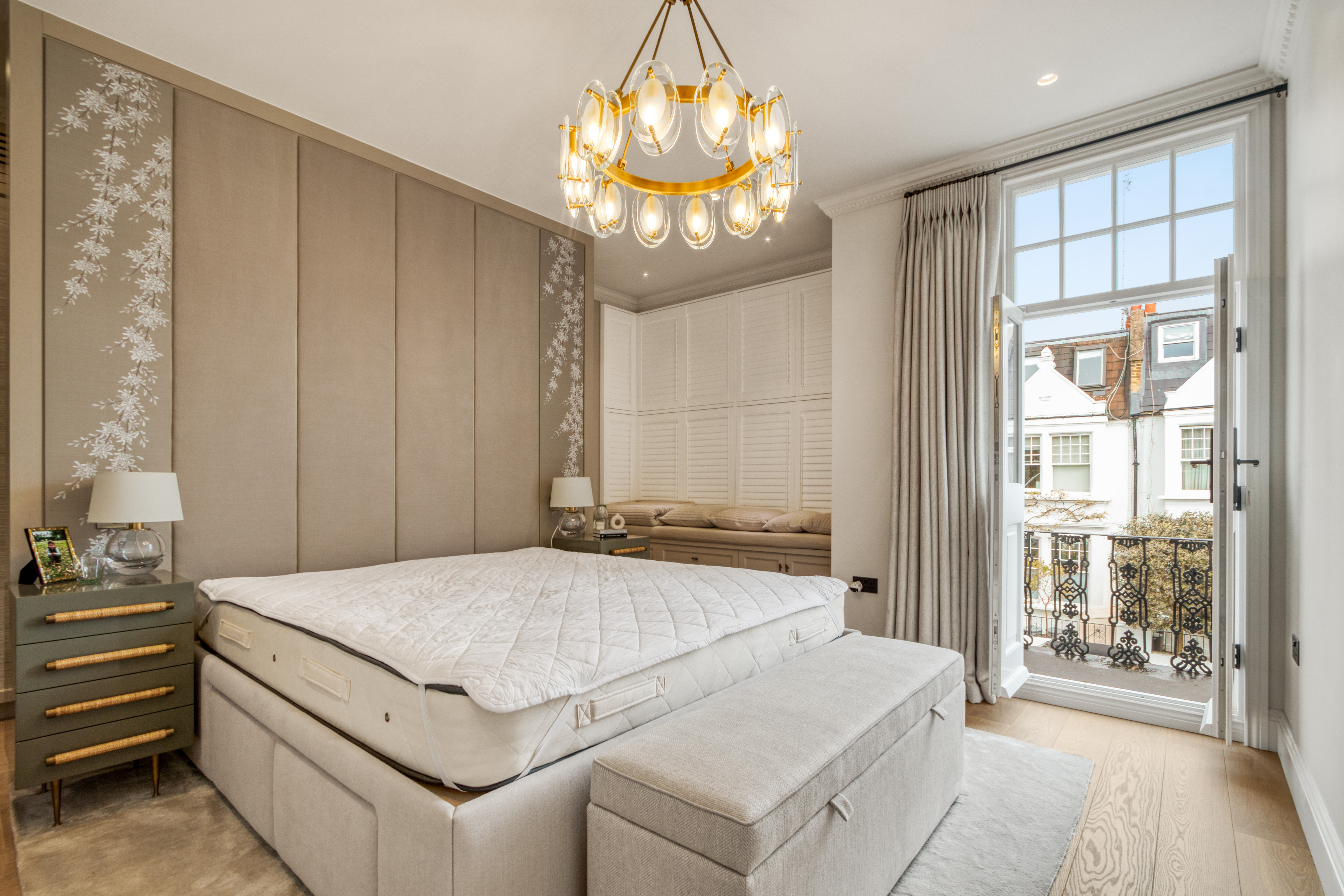 A newly refurbished bedroom featuring a modern design with a large bed, elegant chandelier, and balcony access.