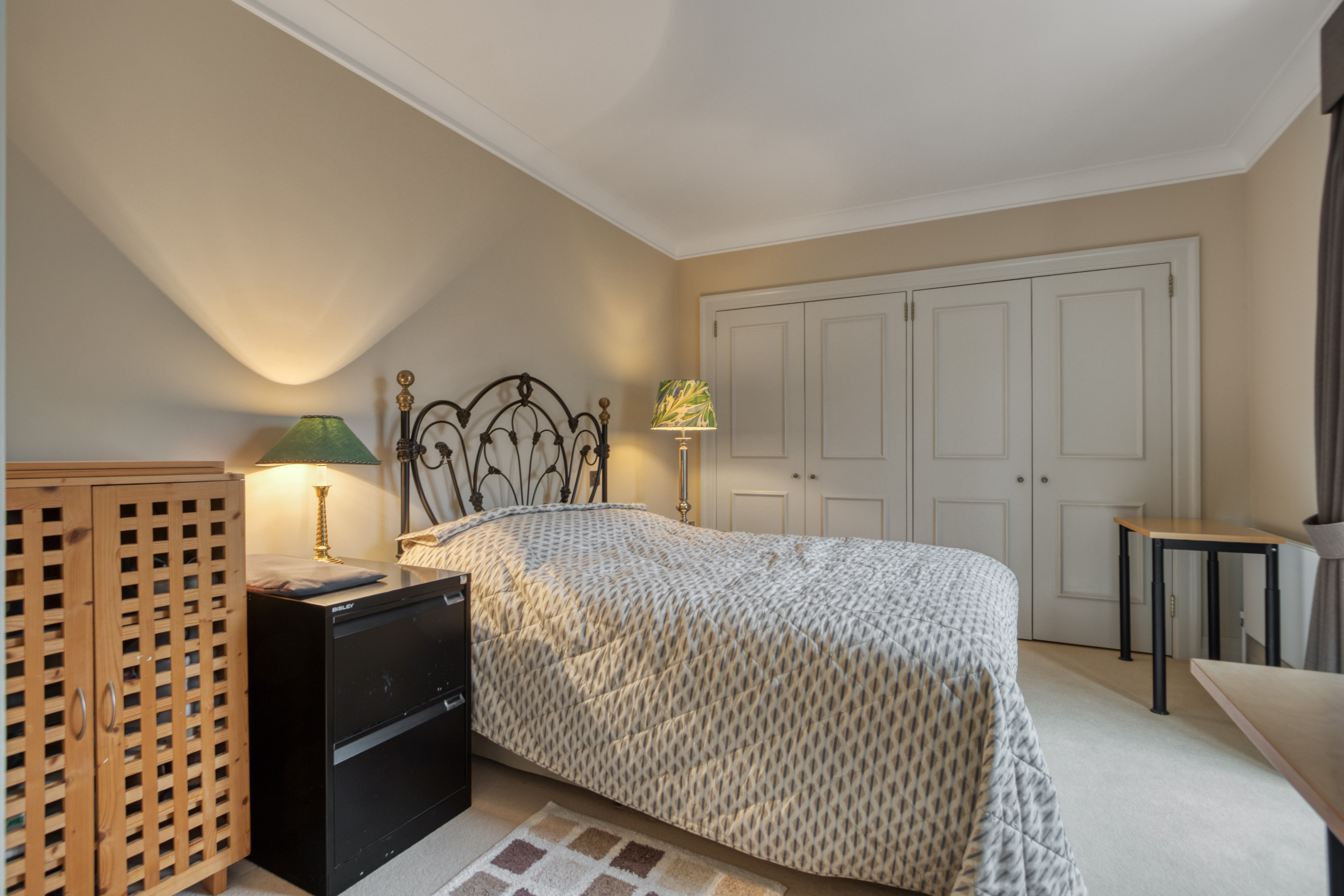 A remodeled bedroom featuring a double bed with metal headboard, built-in wardrobe, and modern lighting.