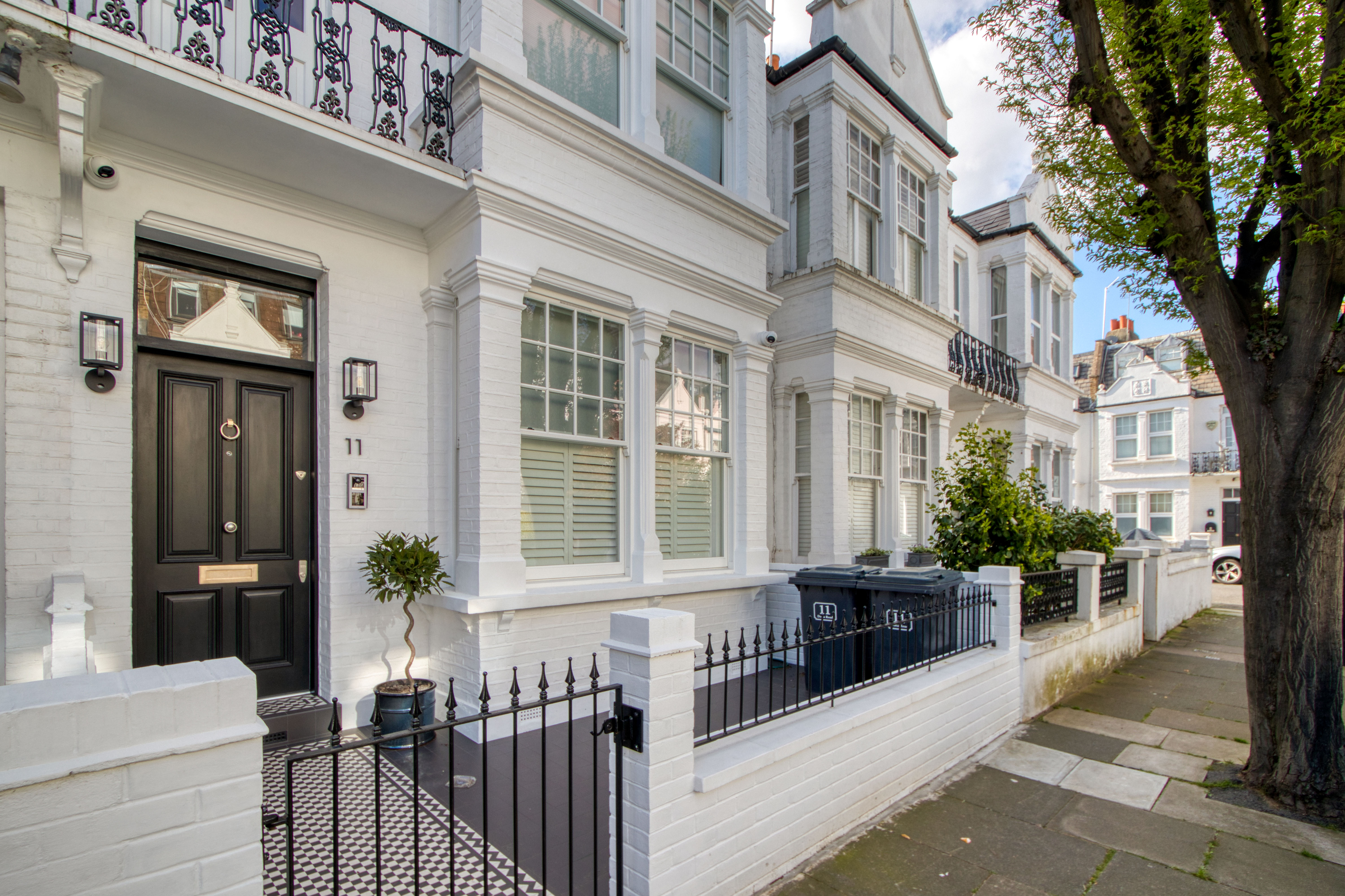 Exterior view of a refurbished white brick residential building with decorative railings and a black front door.