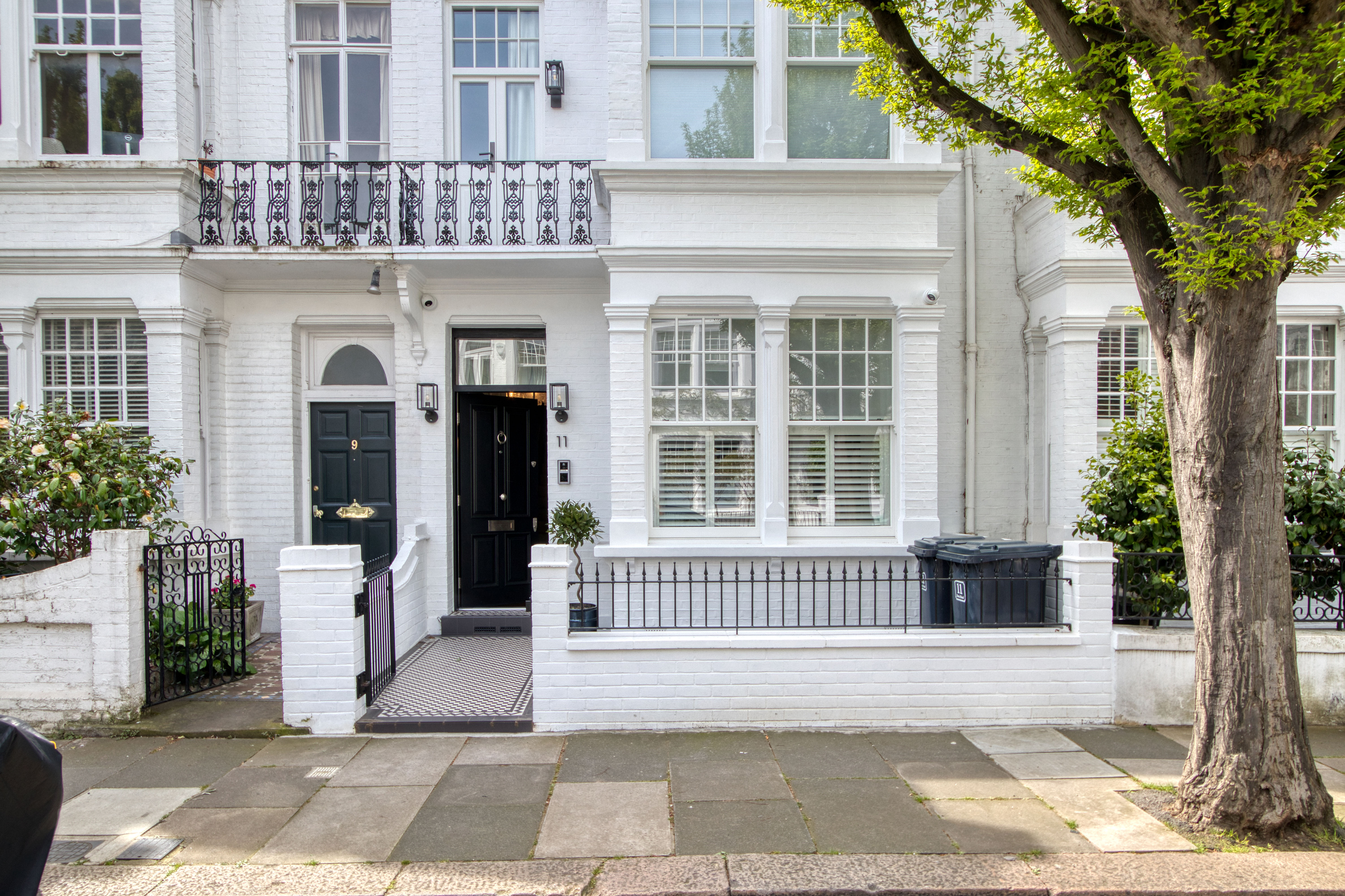 Front view of a refurbished residential property with white brick exterior and ornate black metal railing.