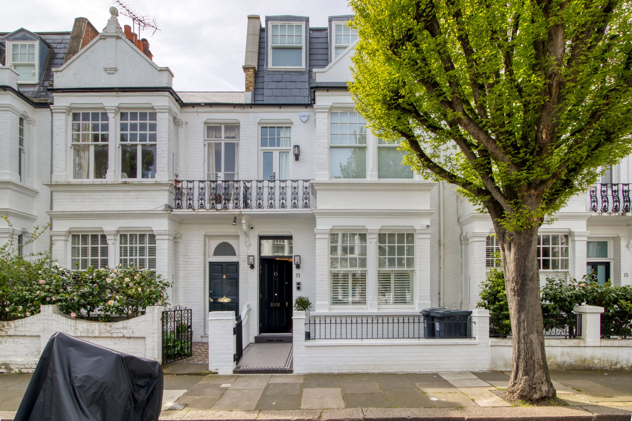 The image shows the exterior front view of a renovated residential home with a classic white brick facade and modern windows.