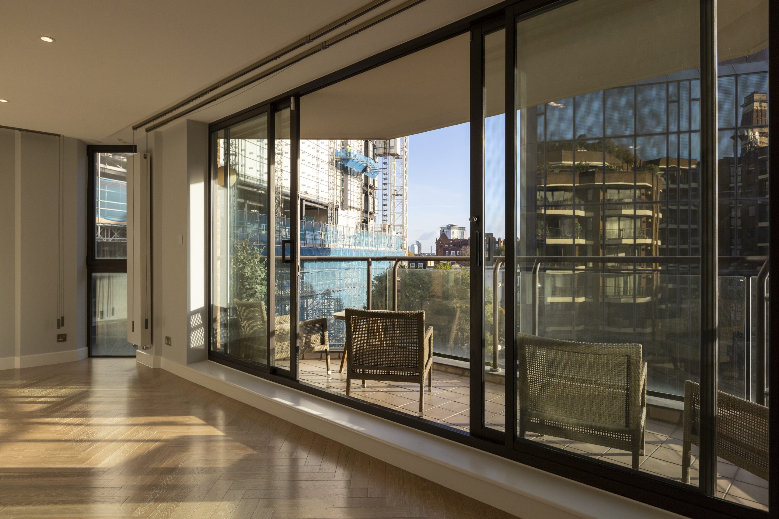 Modern loft extension with large sliding glass doors opening to a balcony overlooking urban construction.
