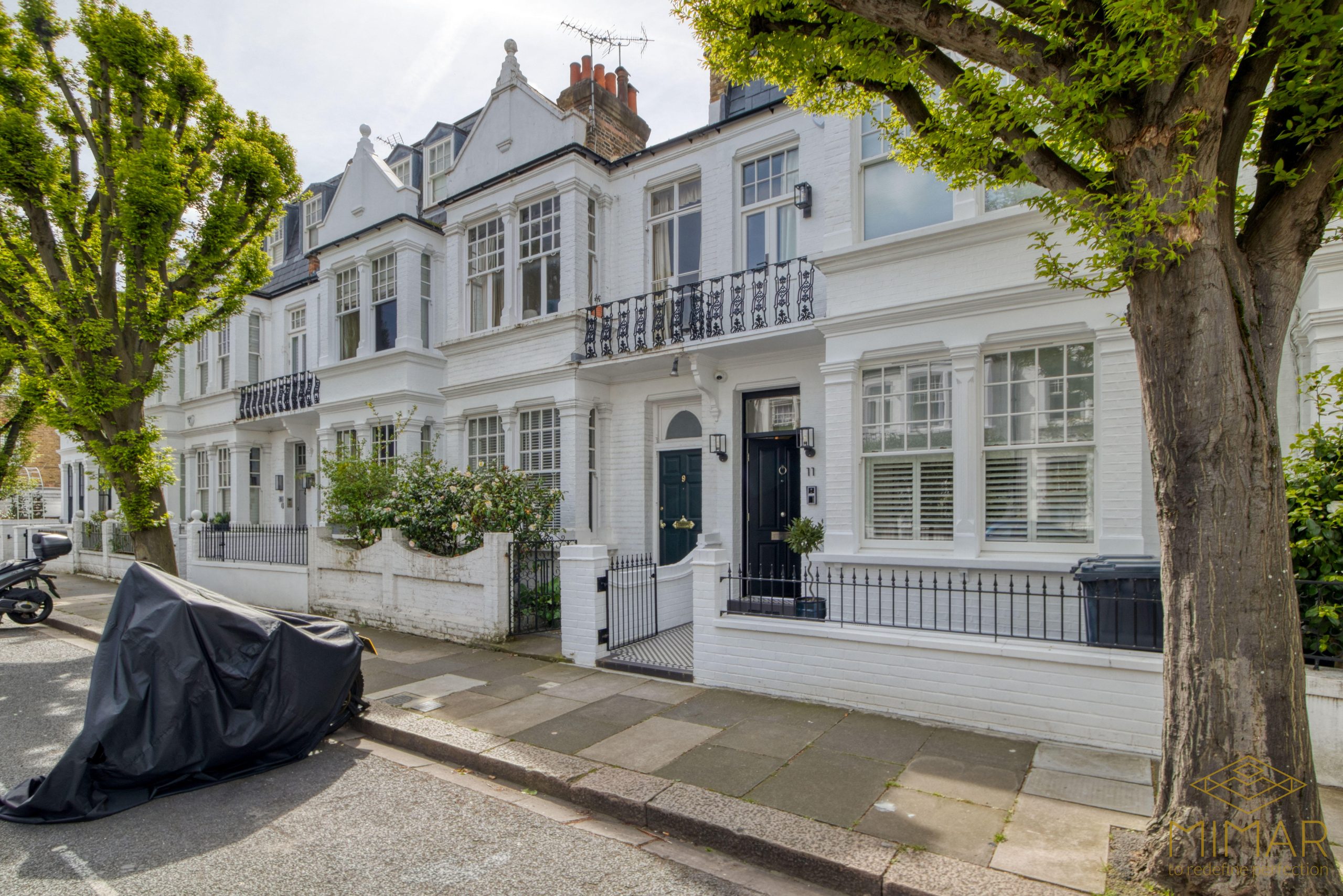 Exterior view of a refurbished row of white terraced houses with detailed facades and a neatly maintained street.
