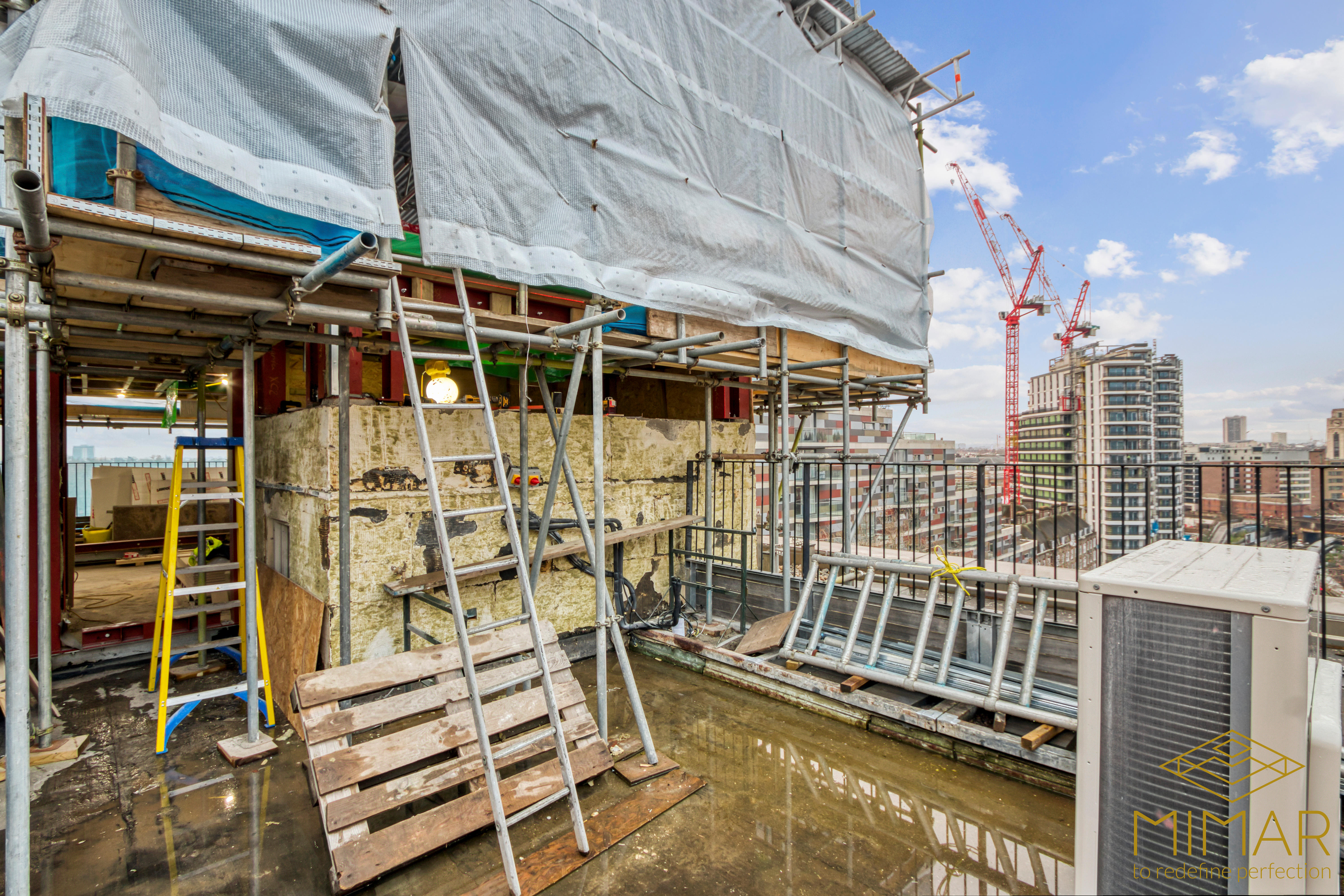 Scaffolding setup on a building's exterior during a renovation project with visible construction materials and equipment.