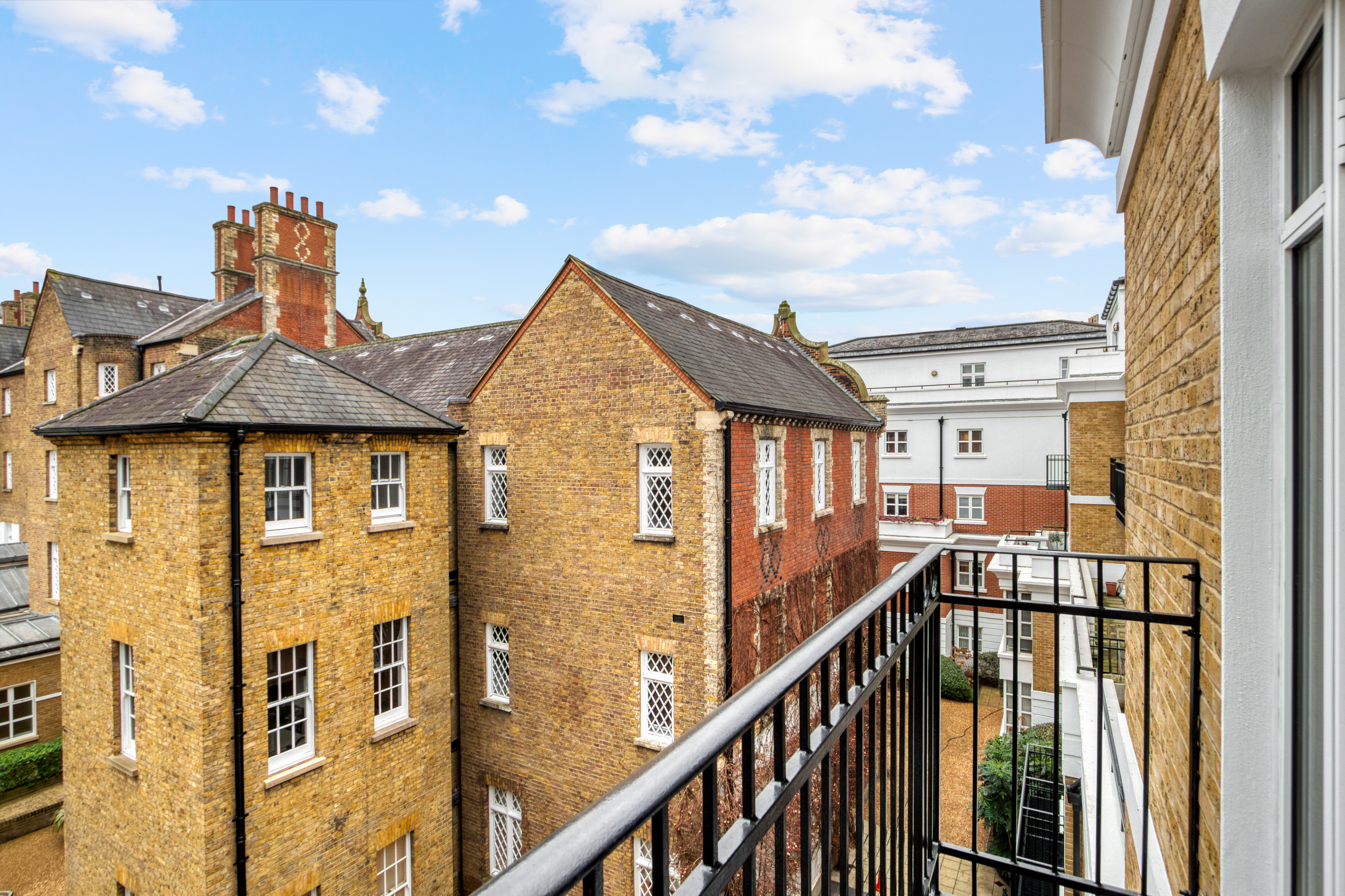 View from a balcony overlooking older residential brick buildings with chimneys and traditional windows.